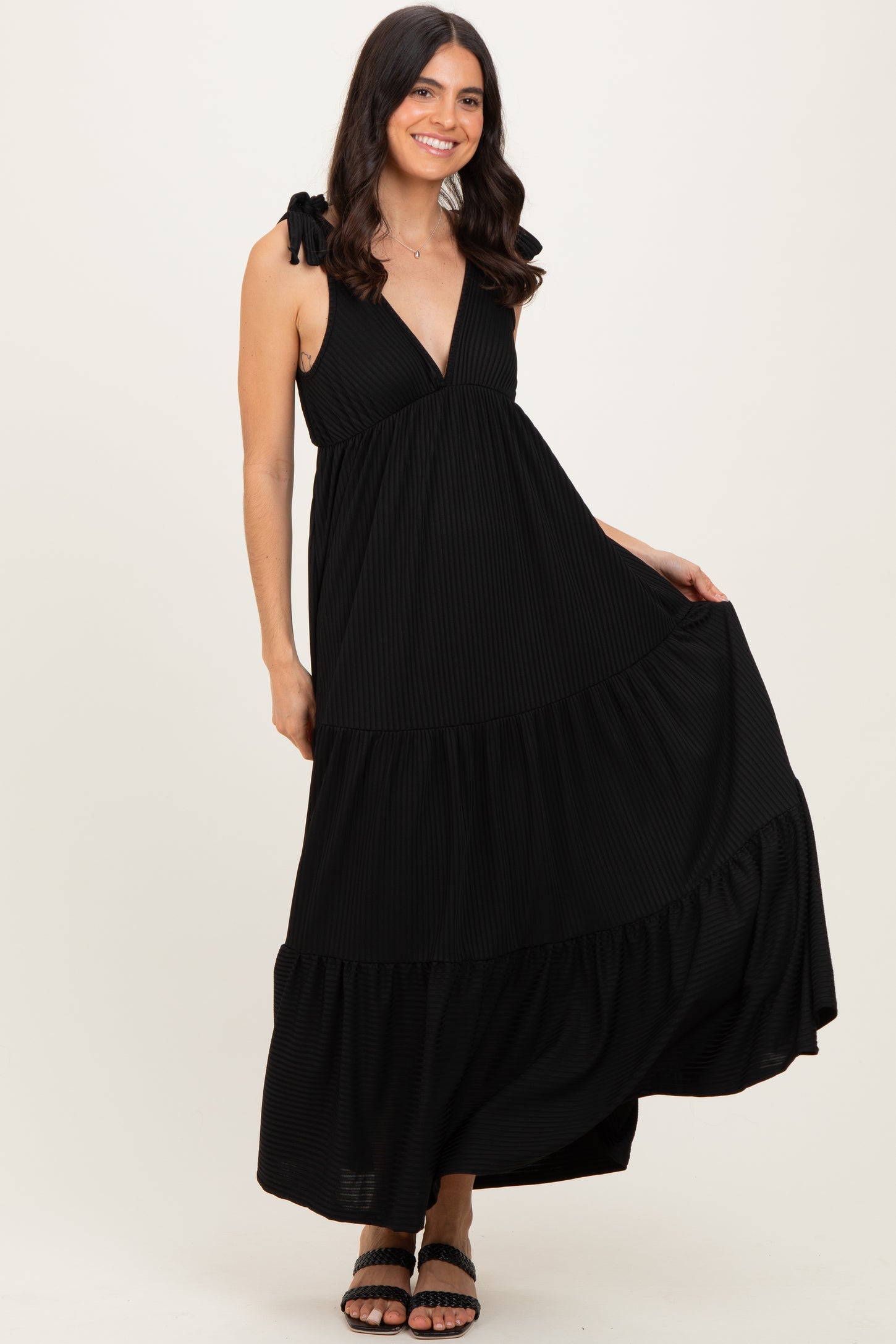 woman wearing a black tiered maxi dress with tie straps and a deep v-neckline
