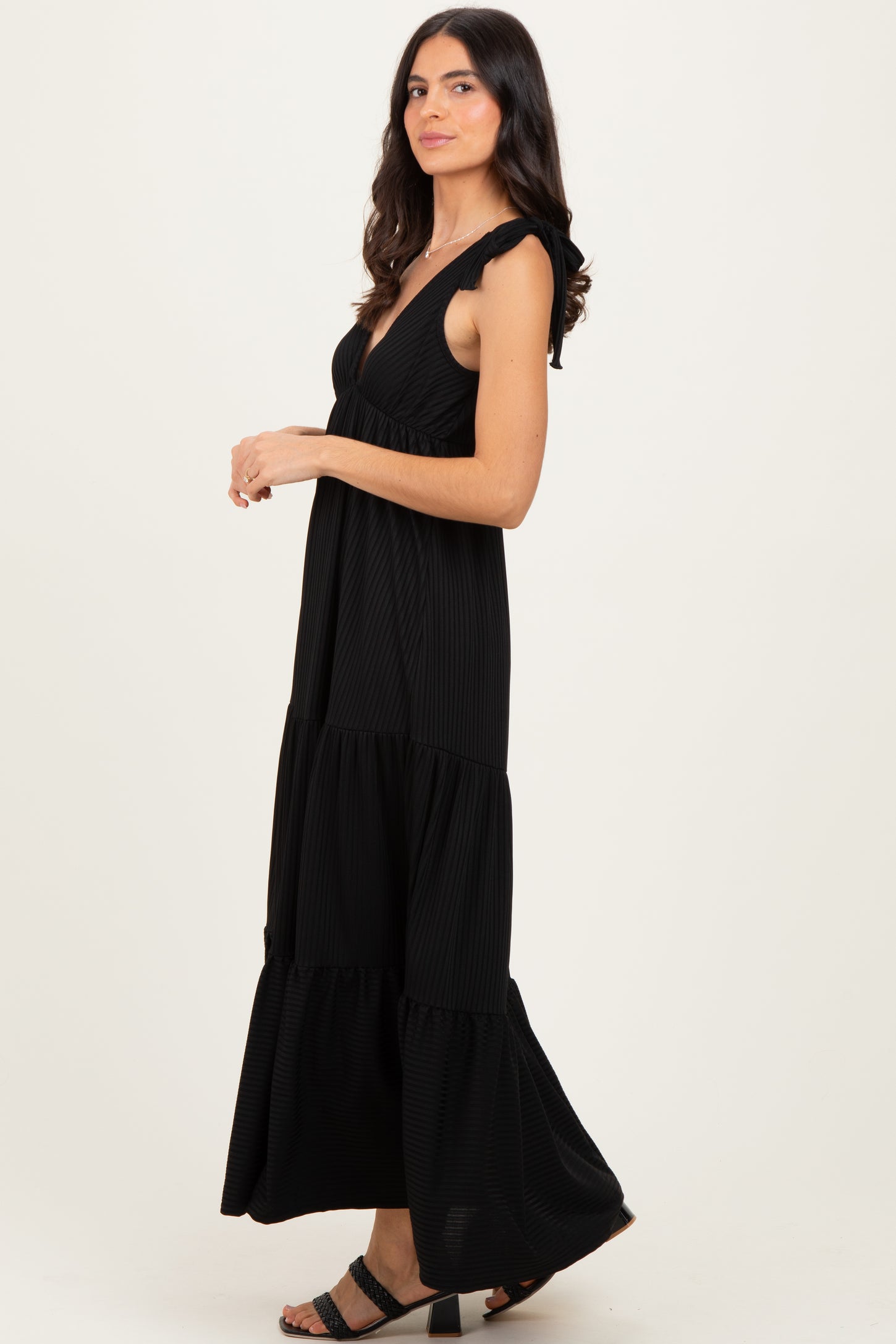 woman wearing a black tiered maxi dress with ruffled straps and a flowy silhouette