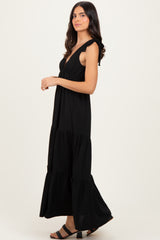 woman wearing a black tiered maxi dress with ruffled straps and a flowy silhouette