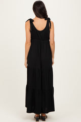 woman wearing a black tiered maxi dress with tie shoulder straps, shown from the back