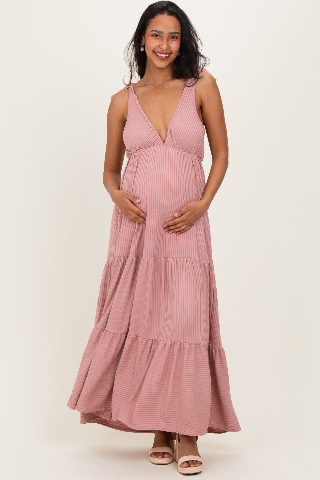 woman wearing a pink striped maternity maxi dress and holding her baby bump