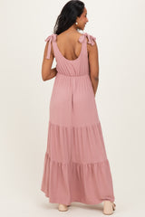 woman wearing a dusty rose maternity maxi dress with tied shoulder straps and a tiered skirt, showing her baby bump from behind