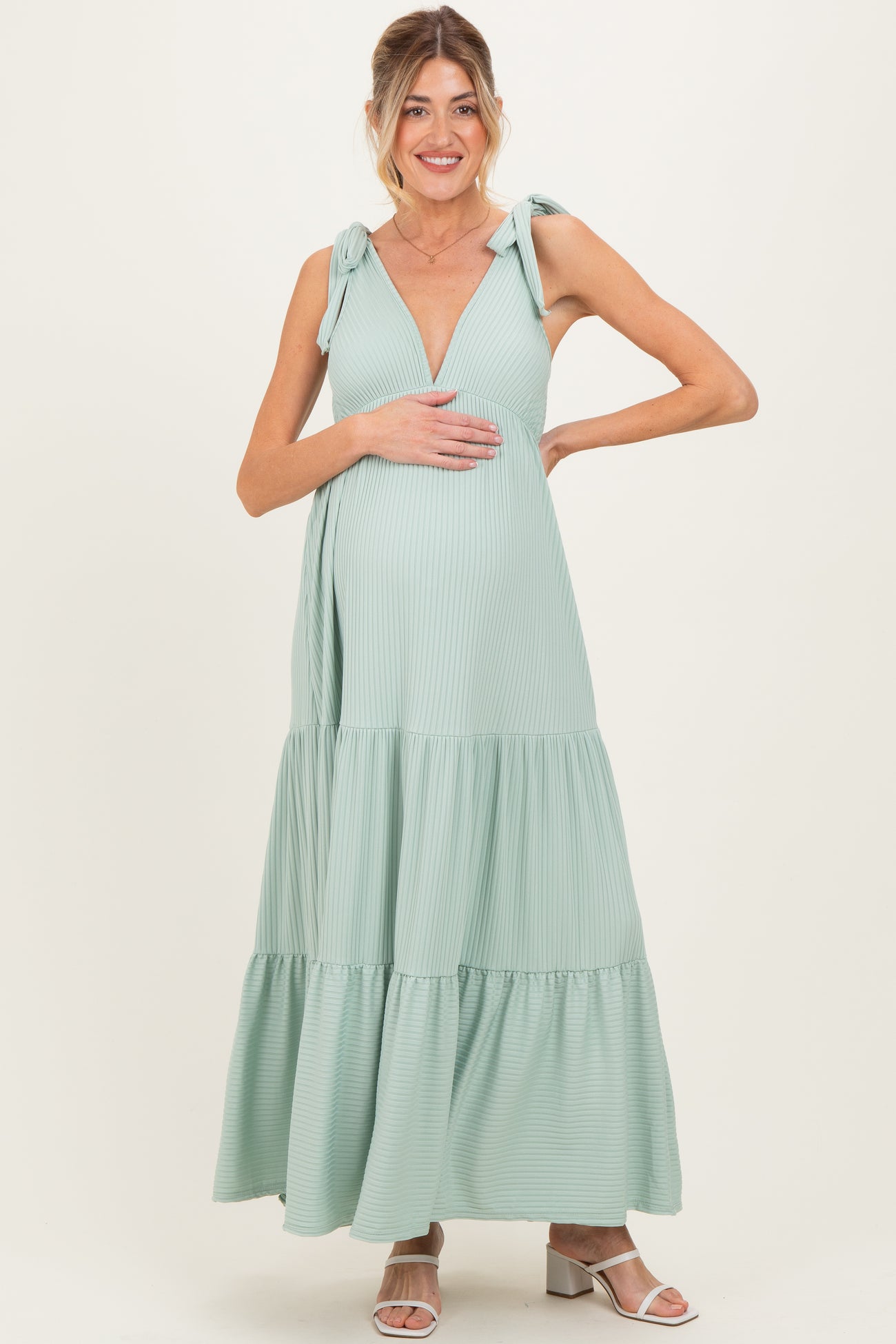 woman wearing a mint green striped maternity maxi dress with tie shoulder straps and a visible baby bump