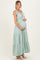woman wearing a light green striped maternity dress with tie straps and a flowing skirt, cradling her baby bump