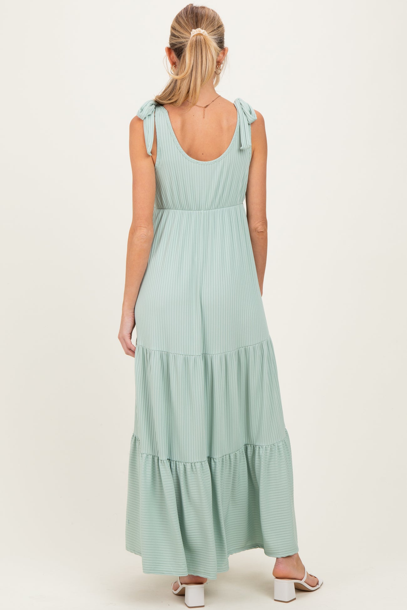 woman wearing a mint green, tiered maternity maxi dress with tie shoulder straps, viewed from the back