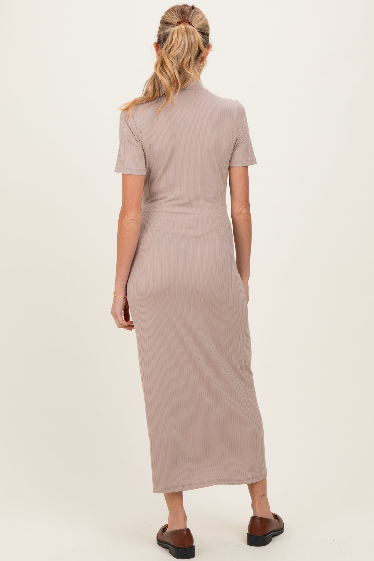 woman wearing a beige ribbed maternity maxi dress, showing the back view with short sleeves and a fitted silhouette