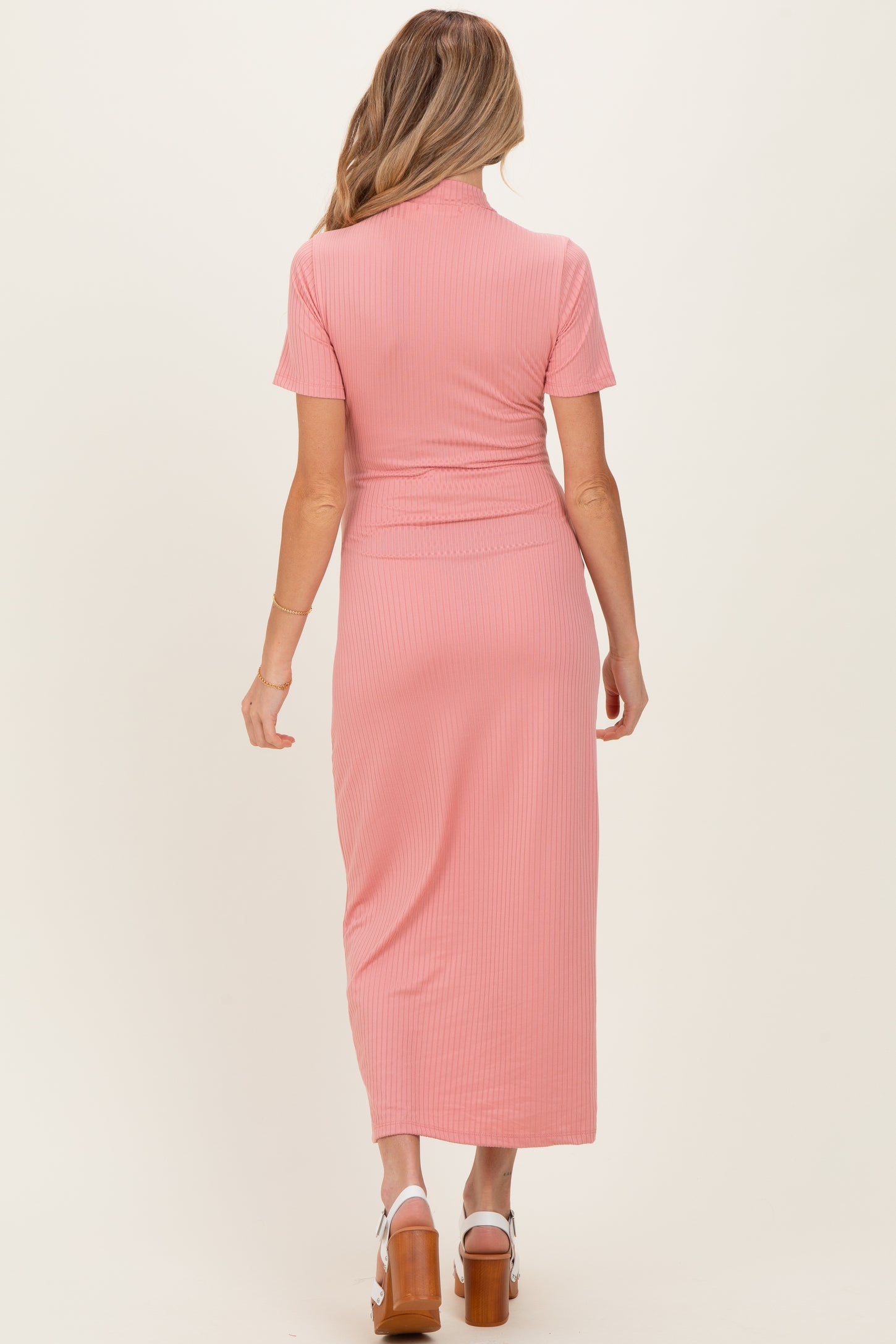 woman wearing a dusty pink ribbed maternity dress with short sleeves and a fitted waist, showing her baby bump