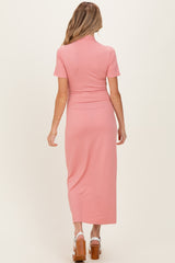 woman wearing a dusty pink ribbed maternity dress with short sleeves and a fitted waist, showing her baby bump