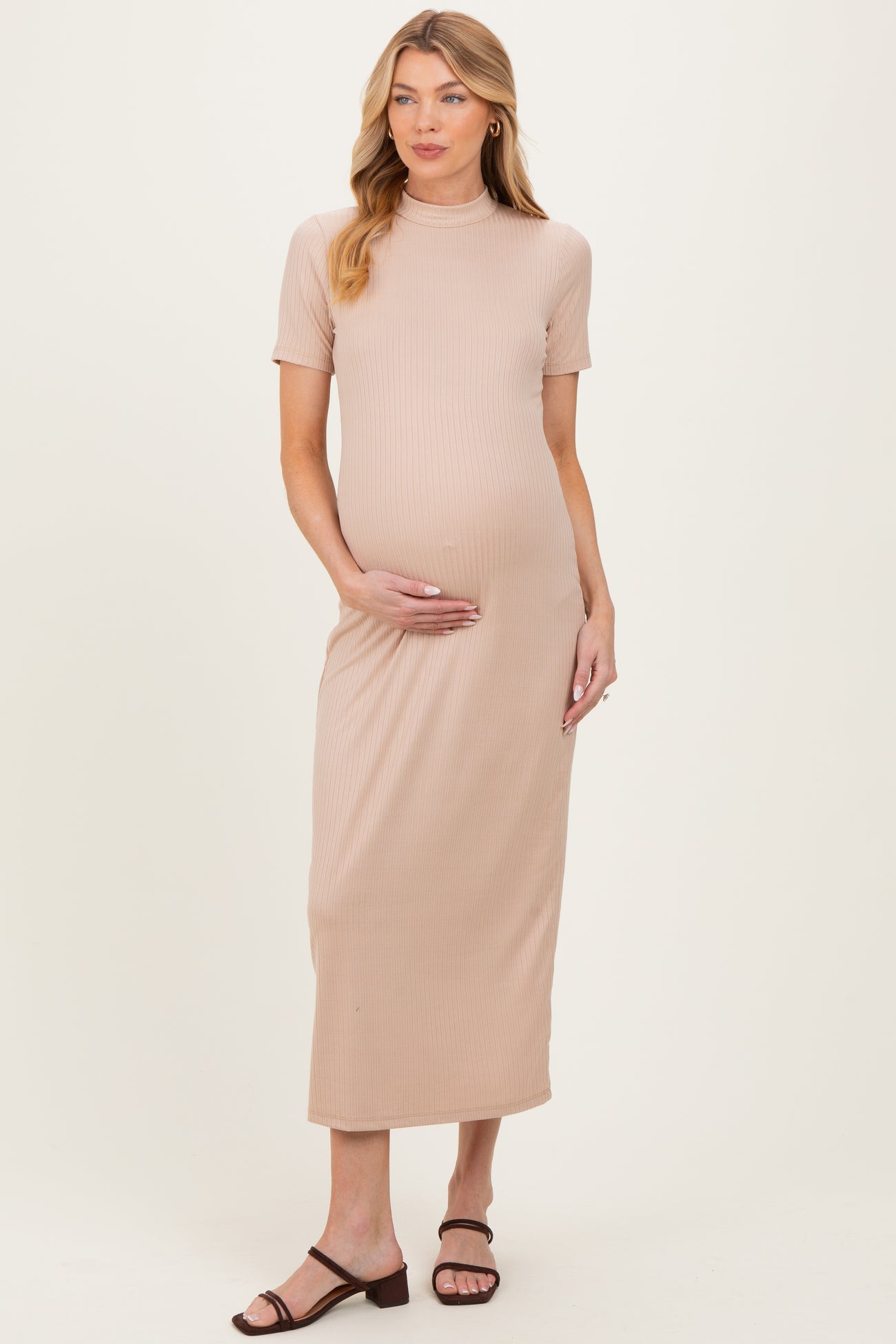 woman wearing a beige ribbed maternity dress with short sleeves and a fitted silhouette, showing her baby bump