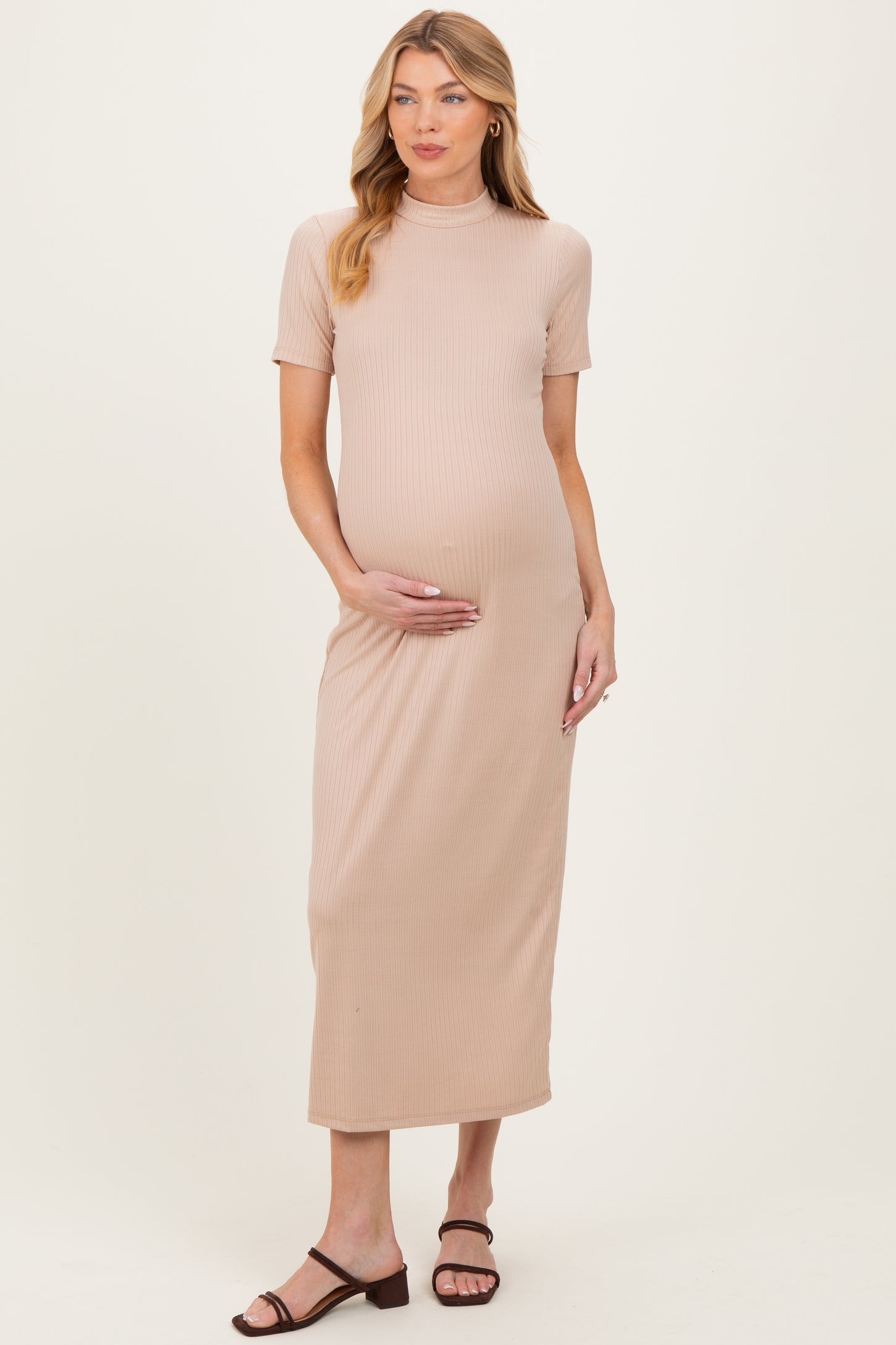 woman wearing a beige ribbed maternity dress with short sleeves and a fitted silhouette, showing her baby bump