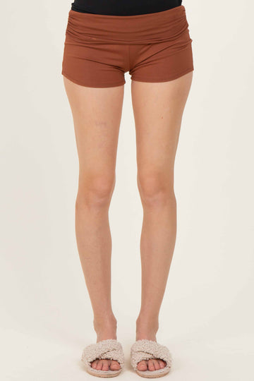 woman wearing brown high-waisted shorts with a fitted style and soft fabric, paired with cozy slippers
