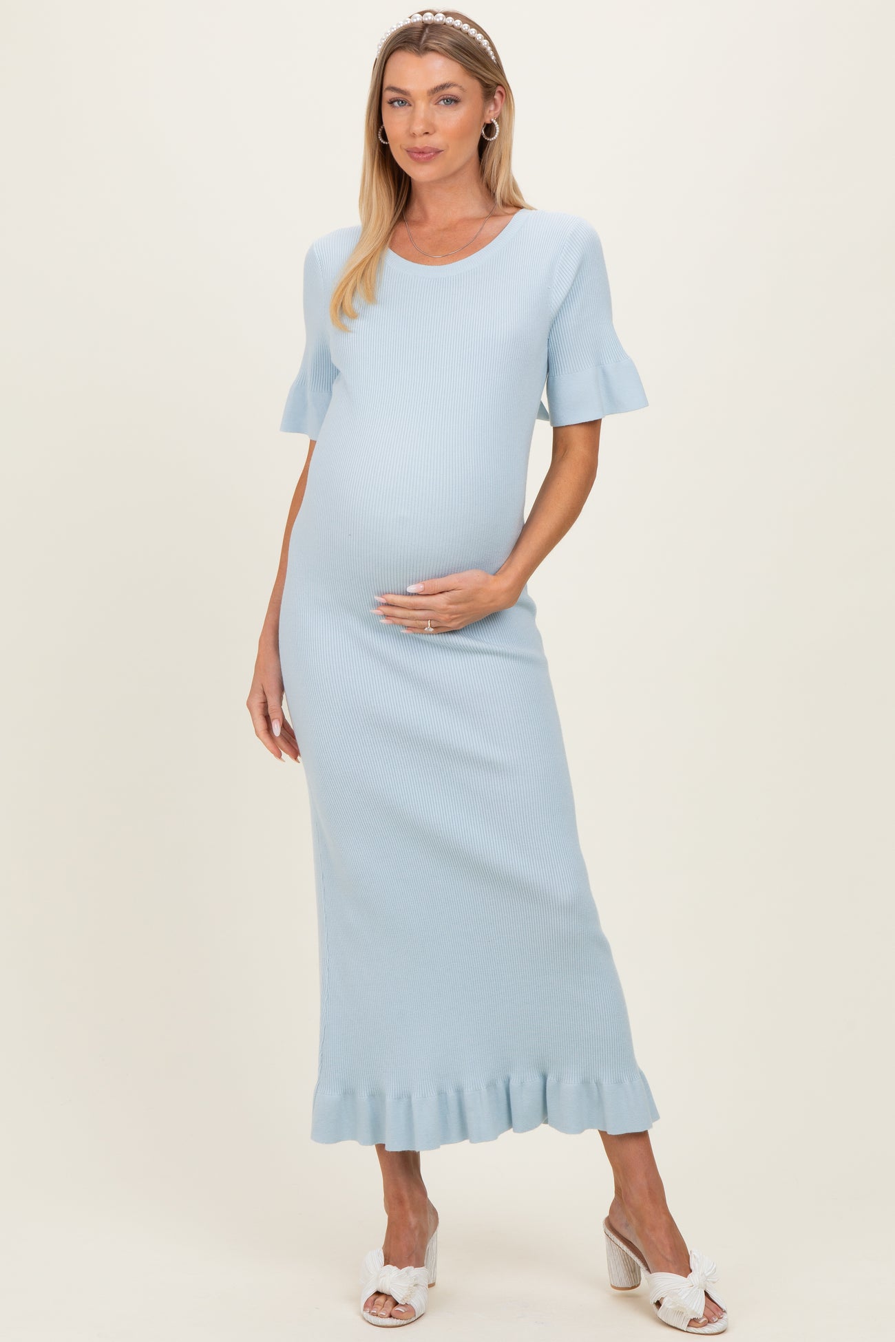woman wearing a light blue ribbed maternity dress with ruffled hem and short sleeves, showcasing her baby bump