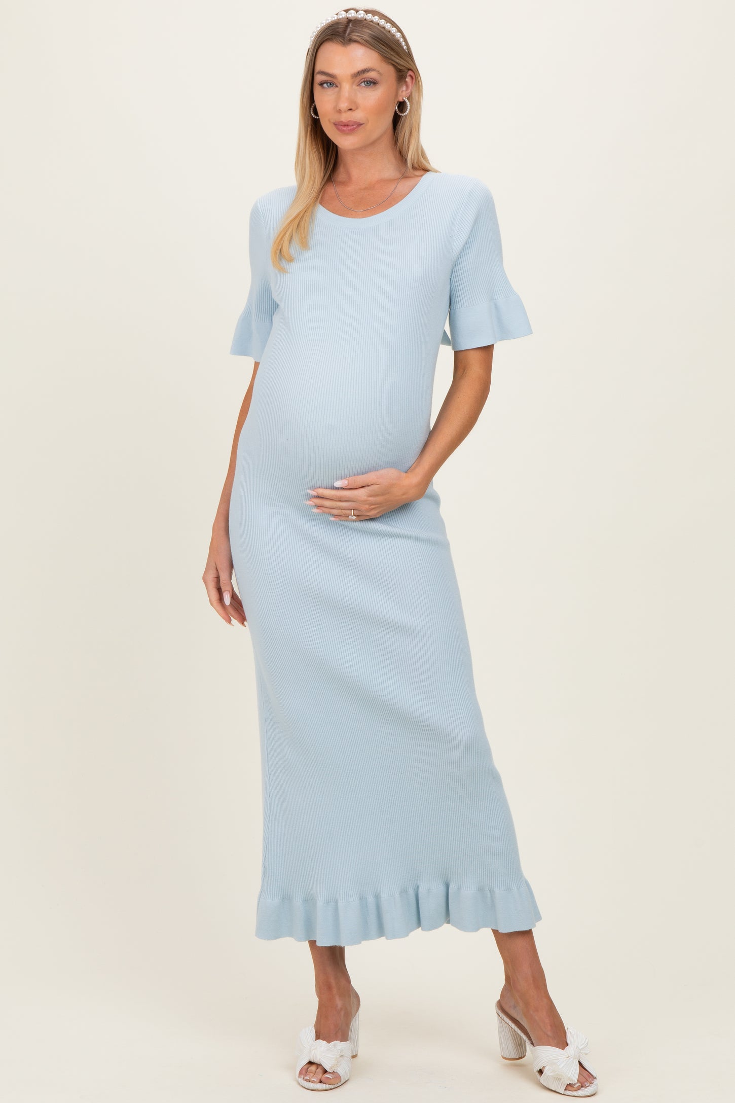 woman wearing a light blue ribbed maternity dress with ruffled hem and short sleeves, showcasing her baby bump
