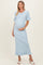 woman wearing a light blue ribbed maternity dress with ruffled hem and short sleeves, showcasing her baby bump