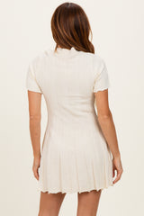 woman wearing a cream short sleeve ribbed knit dress with a fitted silhouette and flared hem