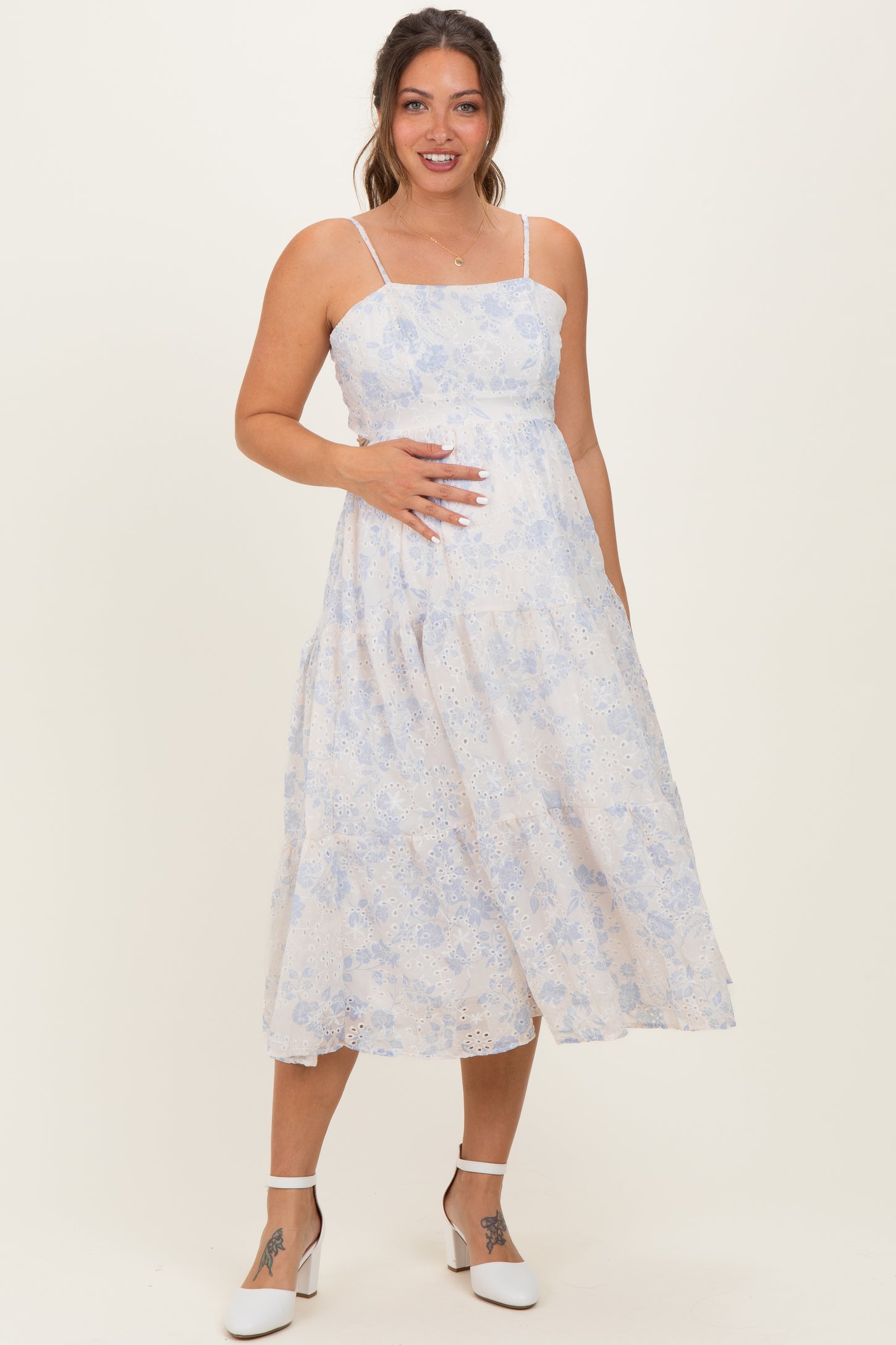 woman wearing a light floral maternity dress with spaghetti straps and a baby bump visible