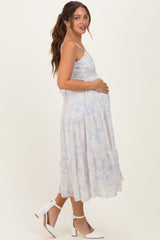 woman wearing a light blue floral maternity dress and holding her baby bump