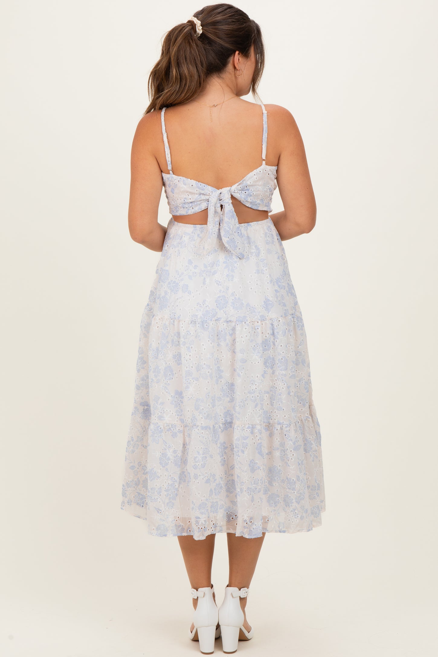 woman wearing a light blue floral maternity dress with a tie-back detail and a layered skirt