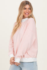 woman wearing a light pink striped sweatshirt with white cuffs and a high collar, smiling at the camera