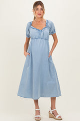 woman wearing a light blue denim maternity dress with short puff sleeves and pockets