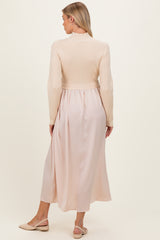 woman wearing a beige maternity dress with a fitted knitted top and flowing silk-like skirt, showing her baby bump