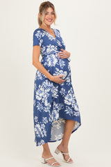 woman wearing a blue floral maternity dress with a high-low hem and holding her baby bump