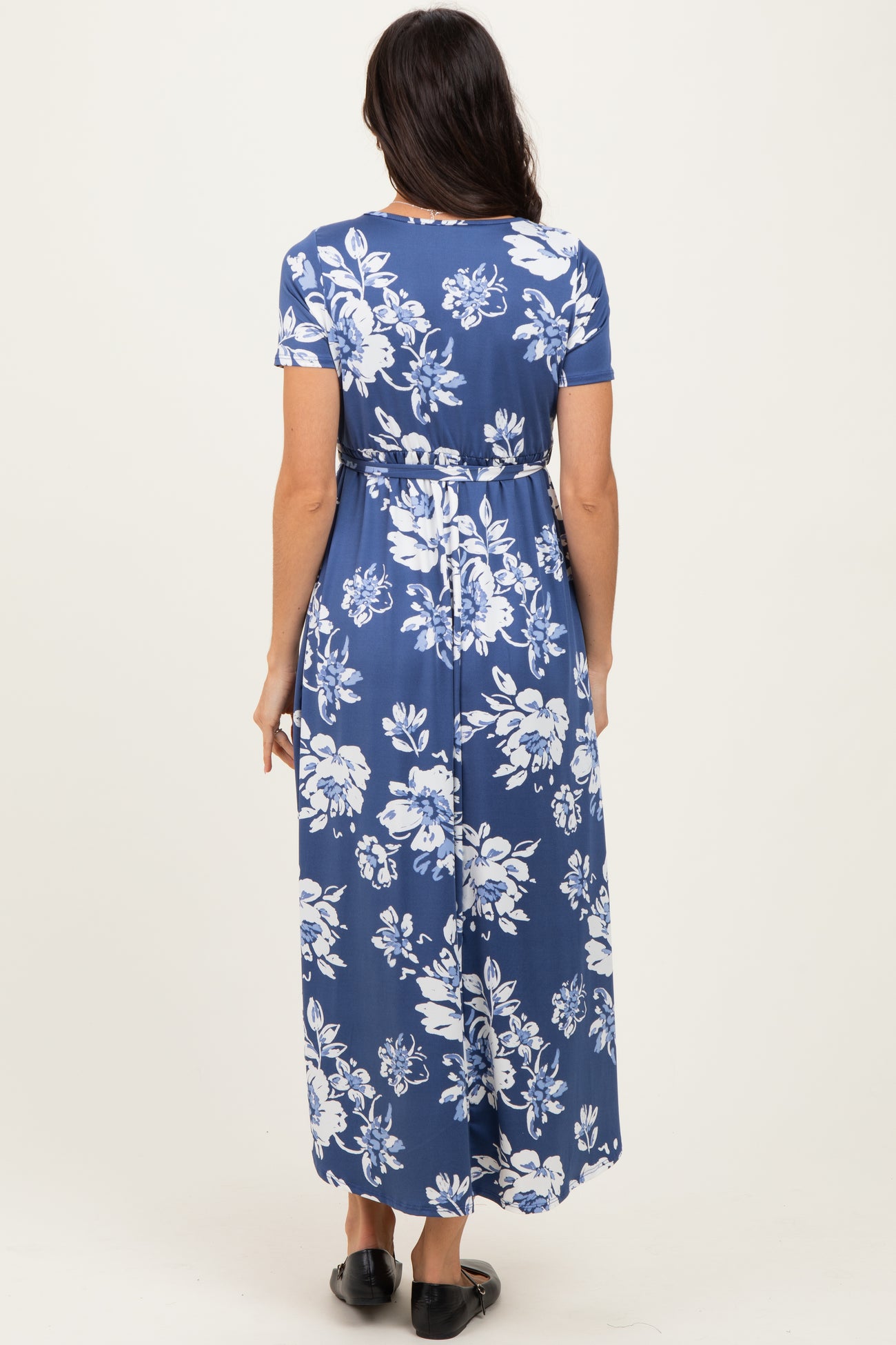 woman wearing a blue floral maxi dress with short sleeves and a tie waist, seen from the back