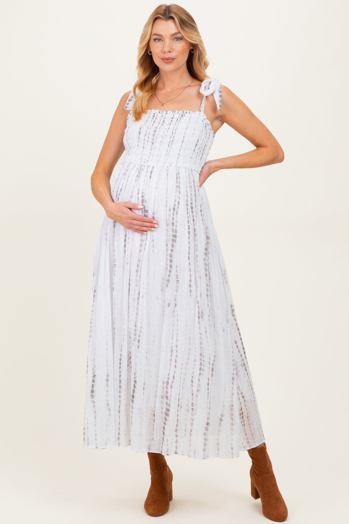 woman wearing a white and brown tie-dye maternity maxi dress with adjustable straps and holding her baby bump