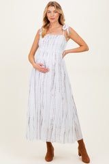woman wearing a white and brown tie-dye maternity maxi dress with adjustable straps and holding her baby bump