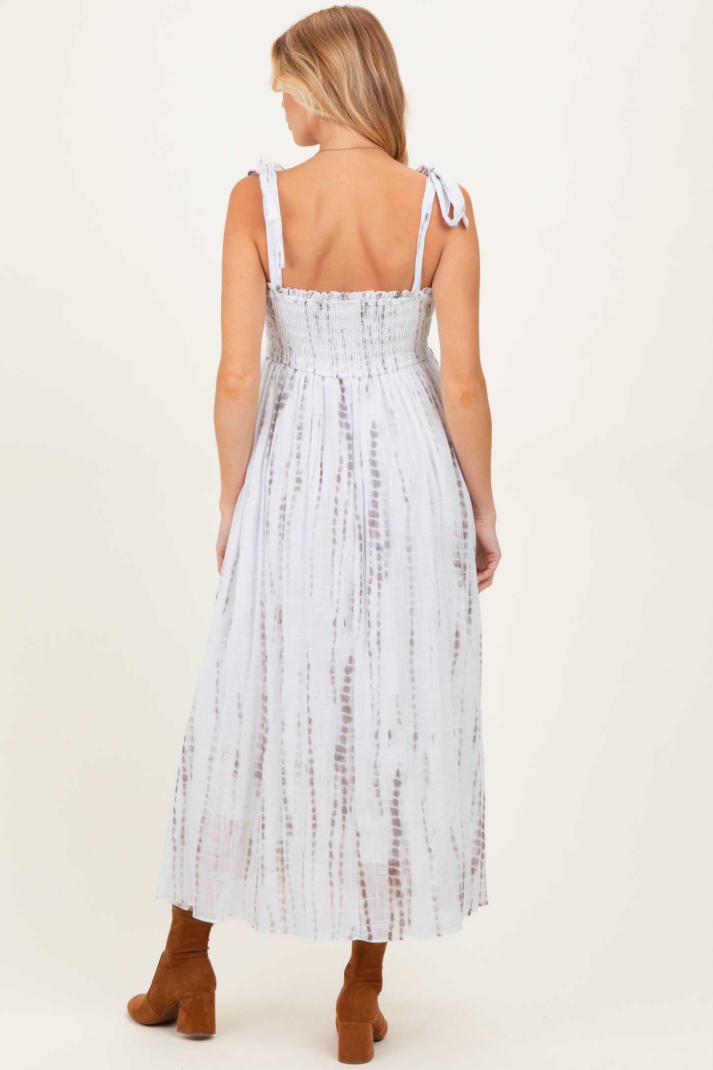woman wearing a back view of a white tie-dye maternity maxi dress with smocked bodice and adjustable straps