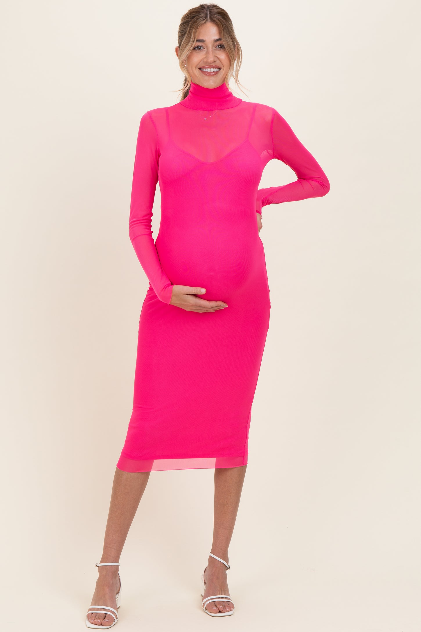woman wearing a hot pink long sleeve maternity dress with a fitted silhouette and holding her baby bump