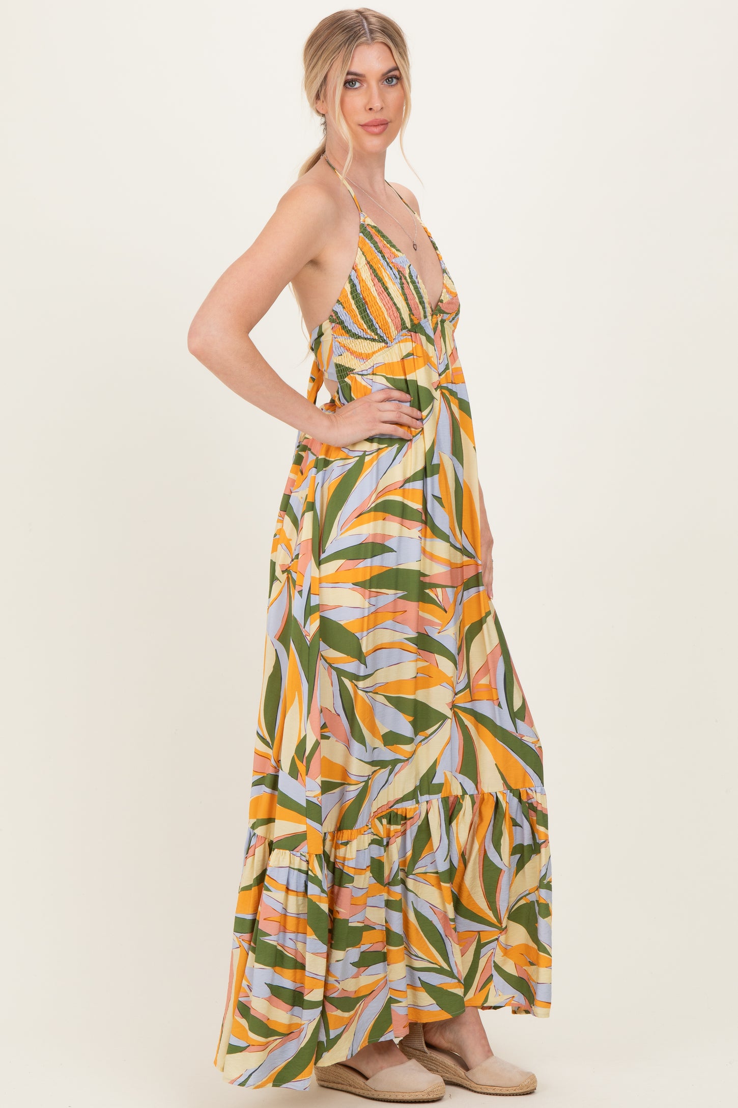woman wearing a colorful maxi dress with a v-neck, spaghetti straps, and a tiered ruffle hem