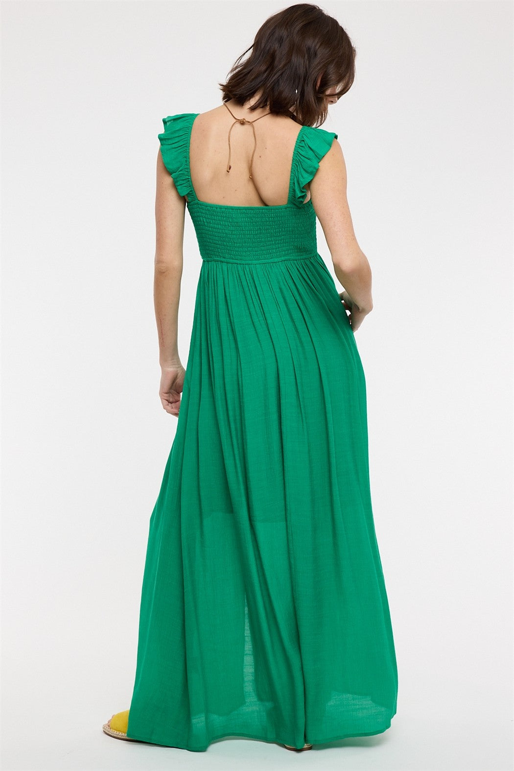 woman wearing a green maxi dress with ruffled sleeves and a smocked bodice, viewed from the back