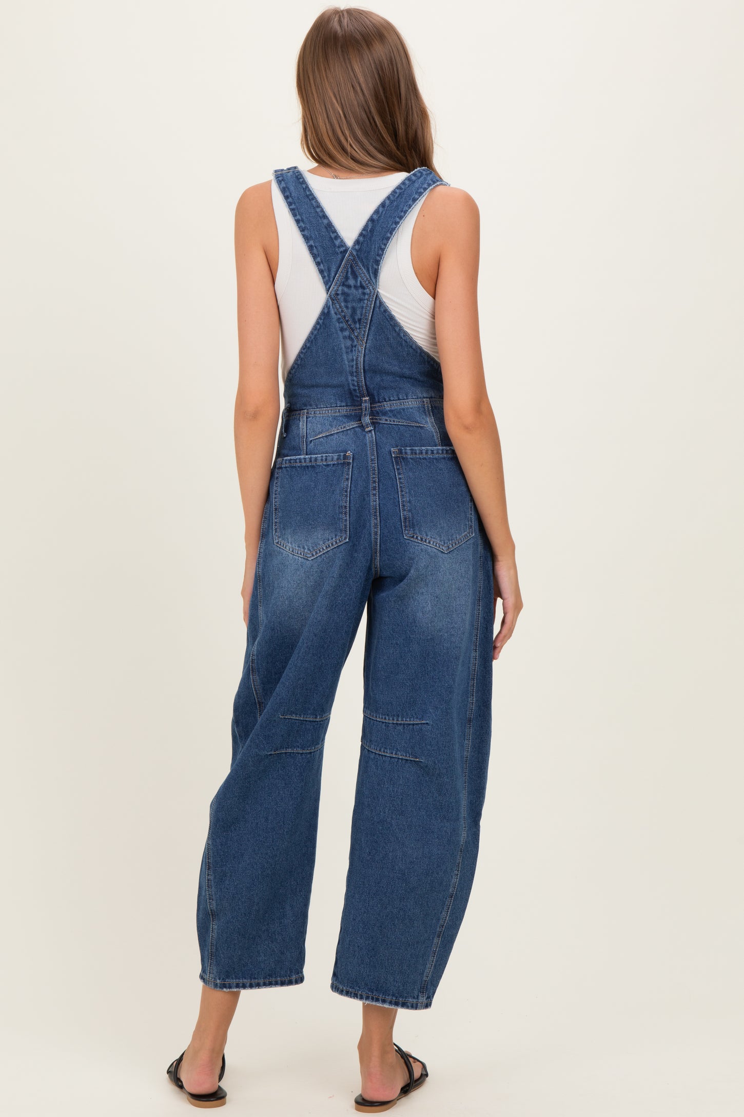 woman wearing a pair of blue denim maternity overalls with wide legs, seen from the back