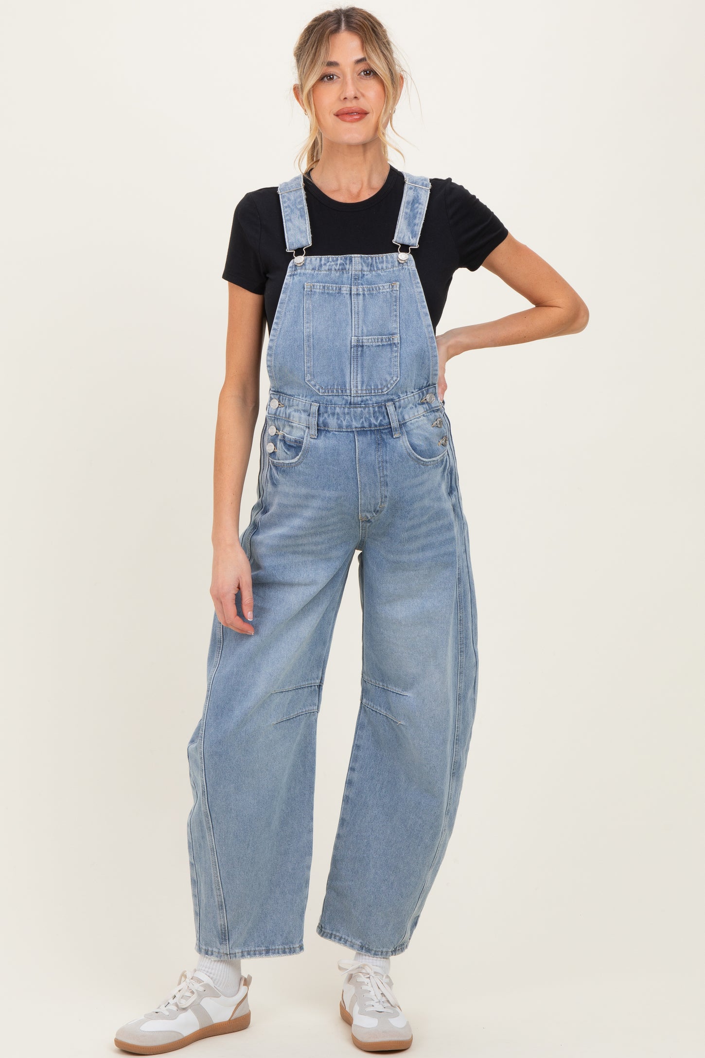 woman wearing light blue denim overalls paired with a black t-shirt, suitable for maternity wear