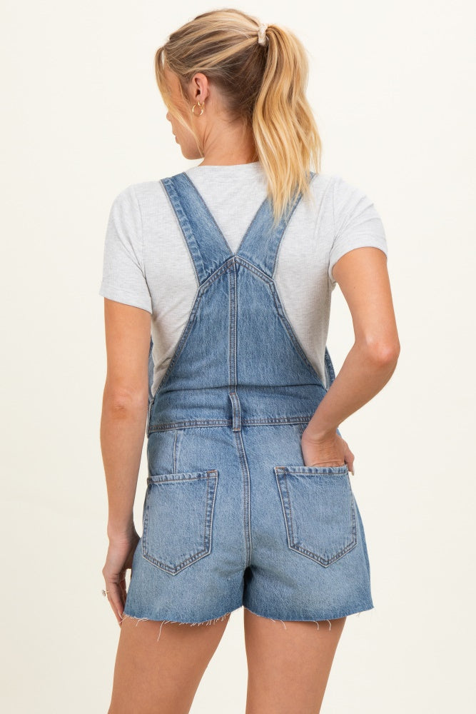 woman wearing a gray t-shirt and blue denim maternity overalls, seen from the back with a casual style