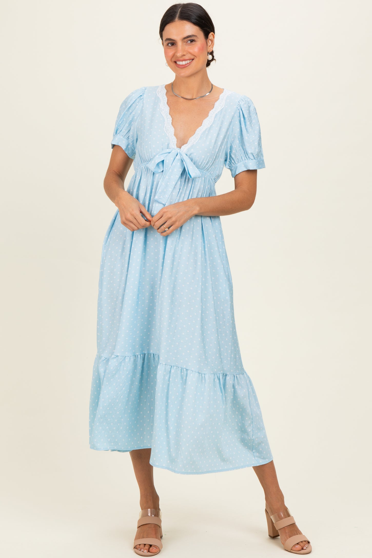 woman wearing a light blue polka dot midi dress with short puff sleeves and a tie-front detail