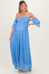 woman wearing a light blue off-the-shoulder maternity maxi dress with puff sleeves and floral print