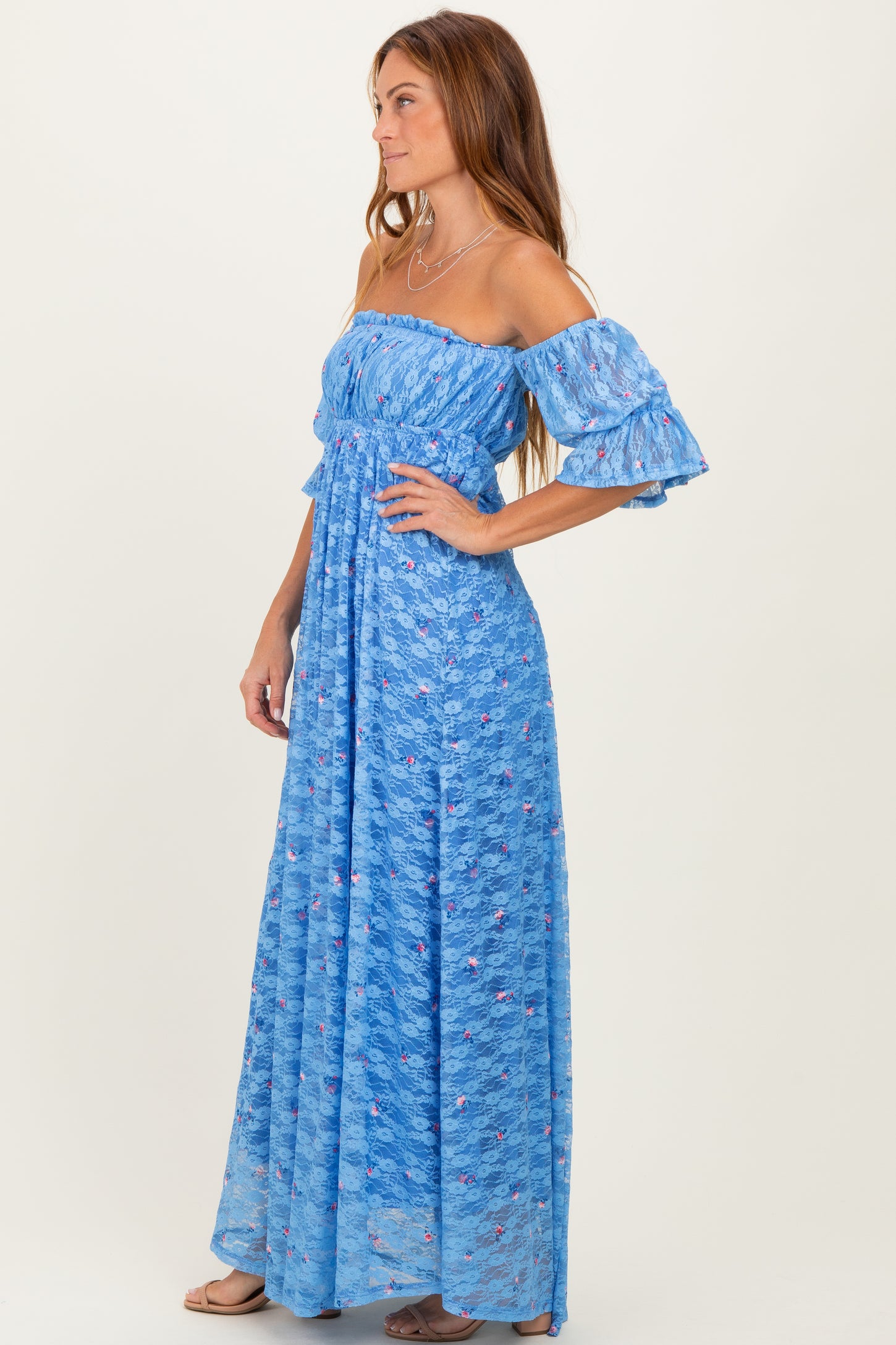 woman wearing a blue off-the-shoulder maxi dress with ruffled sleeves and floral patterns