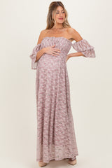 woman wearing a floral off-the-shoulder long pink maternity dress and holding her baby bump