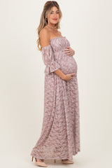 woman wearing a mauve off-shoulder floral maternity dress and holding her baby bump