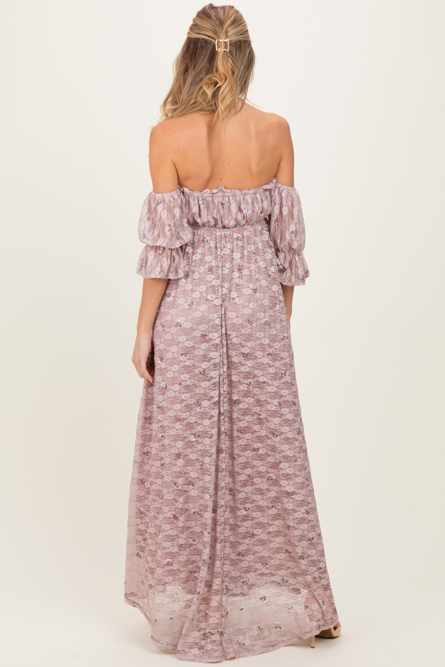 woman wearing a lilac off-the-shoulder maternity maxi dress with puffed sleeves and floral print, showing her back