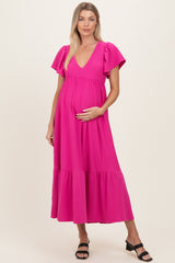 woman wearing a bright pink polka dot maternity dress with flutter sleeves and a baby bump visible