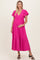 woman wearing a bright pink polka dot maternity dress with flutter sleeves and a baby bump visible