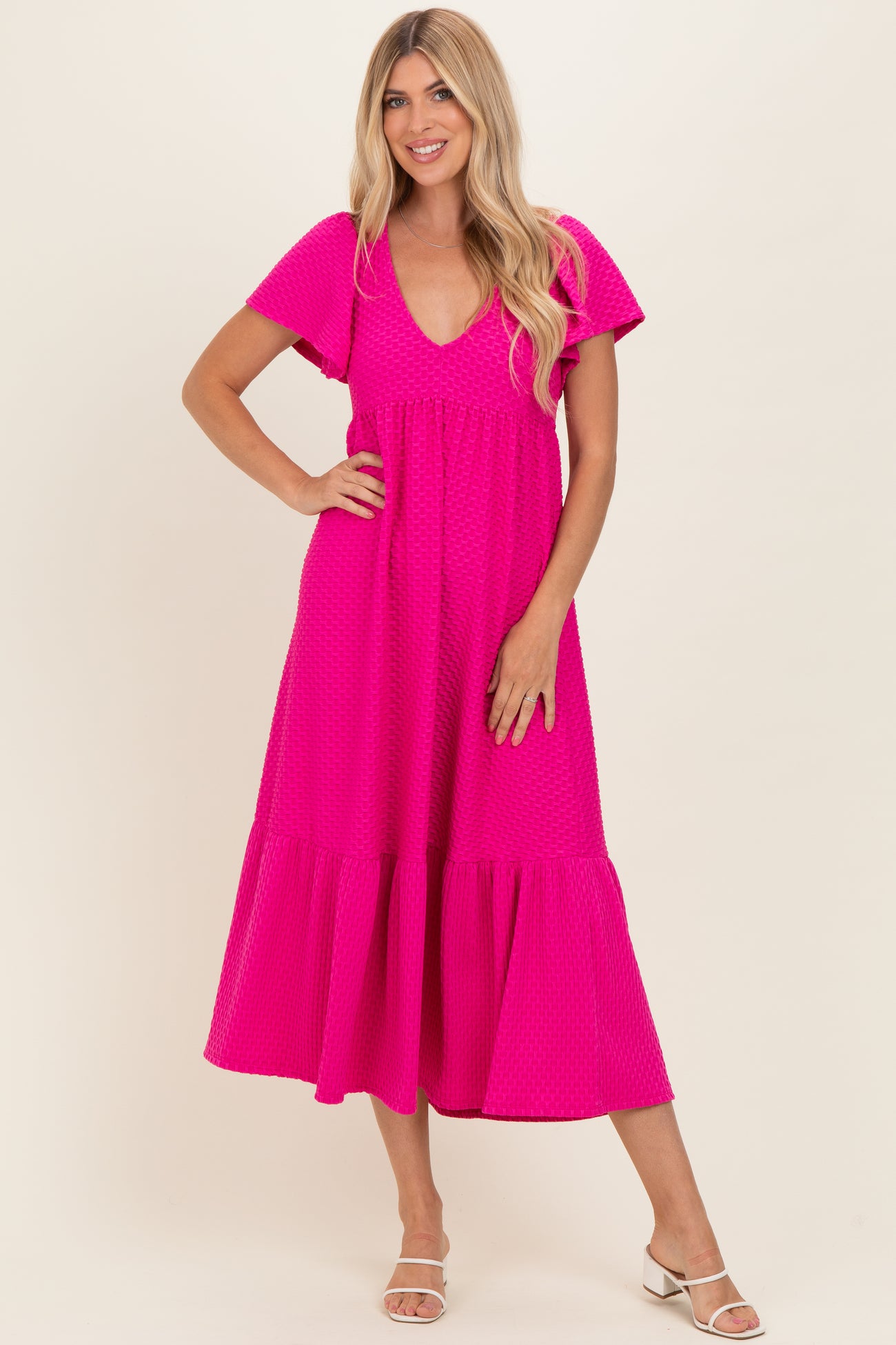 woman wearing a bright pink short sleeve maxi dress with a tiered hem and v-neckline