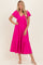 woman wearing a bright pink short sleeve maxi dress with a tiered hem and v-neckline