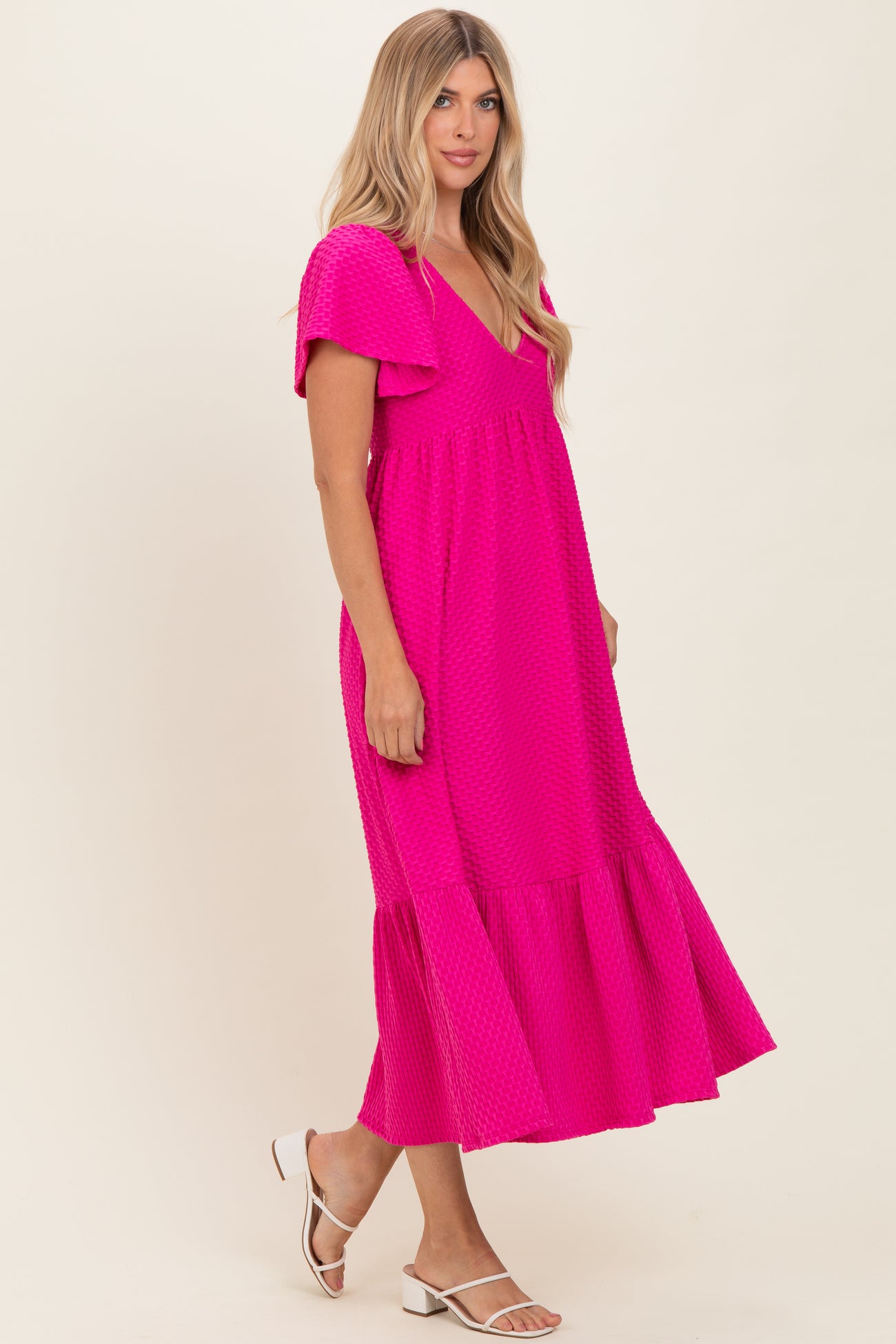 woman wearing a bright pink short sleeve maxi dress with ruffle details and a flared hem