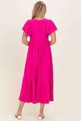 woman wearing a bright pink puff sleeve maxi dress with a tiered skirt, standing with her back to the camera