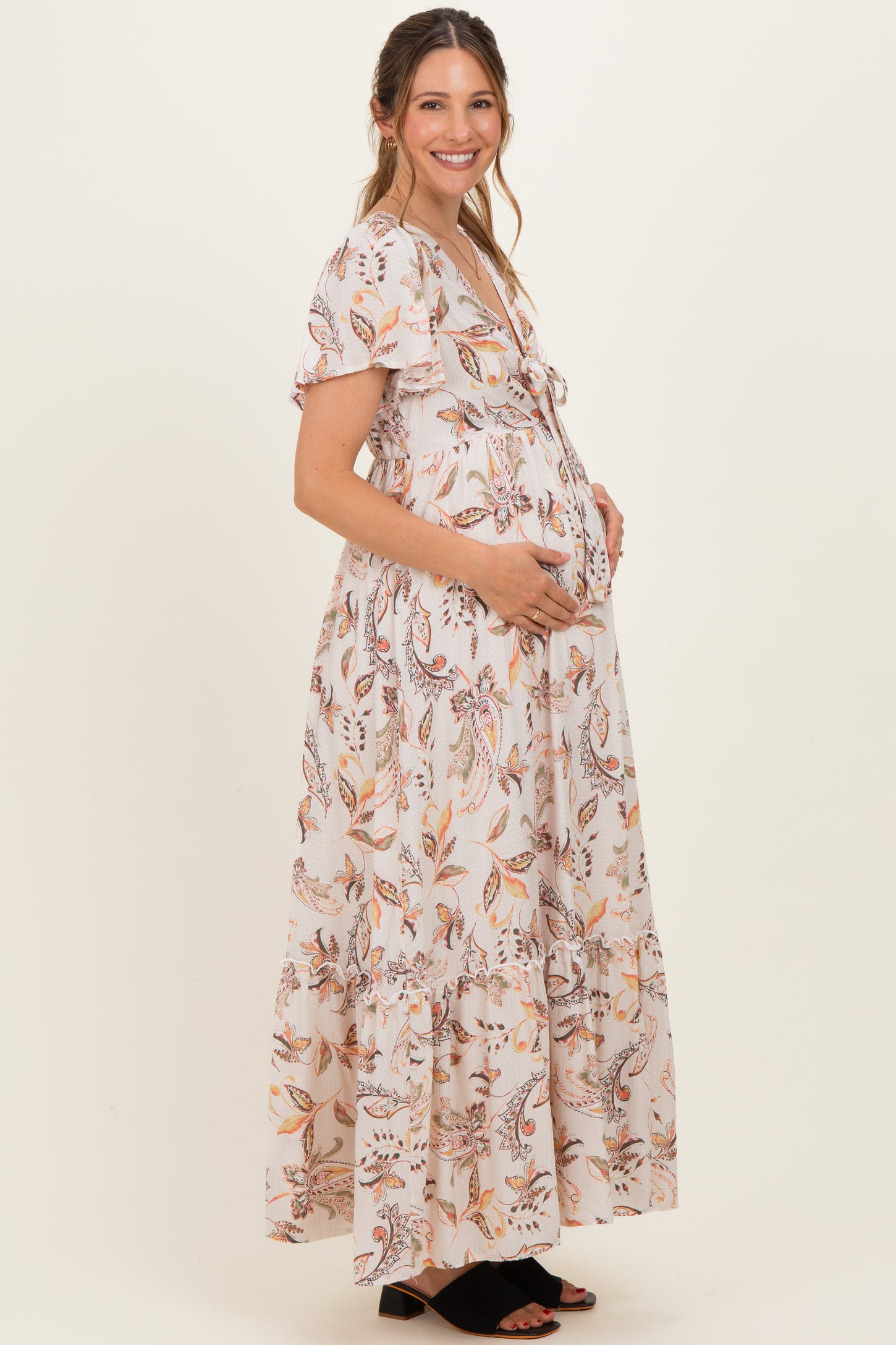 woman wearing a floral print maternity maxi dress and holding her baby bump