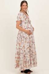 woman wearing a floral print maternity maxi dress and holding her baby bump